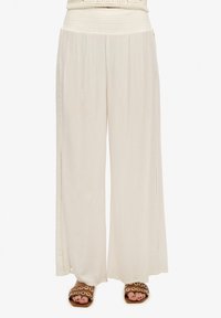 Pantalones de pierna ancha en una suave y ligera tela, color beige cremoso, con cinturilla fruncida y detalles de abertura lateral.