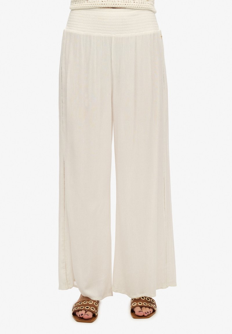 Pantaloni ampi in tessuto morbido e leggero, colore beige cremoso, con vita arricciata e dettagli con spacchi laterali.