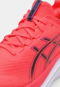 Helle pinkfarbene Laufschuhe aus strukturiertem Material, mit schwarzen Akzenten und Schnürsenkeln, sowie einem markanten ASICS-Logo auf der Zunge.