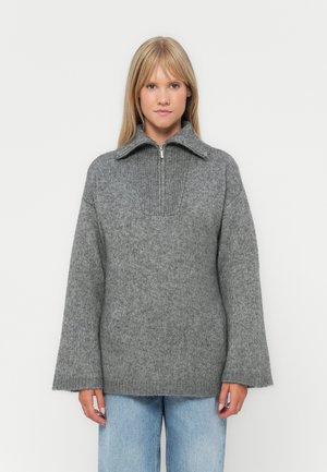 Gray pullover sweater with a quarter-zip, ribbed collar, wide sleeves, and a textured knit pattern, displayed over light blue jeans.