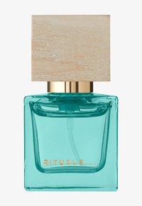 Bouteille de parfum en verre transparent avec un liquide turquoise, dotée d'un capuchon doré et d'un couvercle en bois texturé. L'étiquette indique "RITUALS..." en doré.