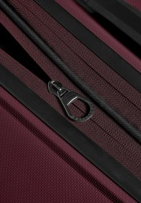 Close-up of a maroon textured fabric with a partially open black zipper and a metal zipper pull tab.