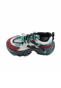 Masywne sneakersy w kolorze teal, bordo, czarnym i szarym z czarnymi sznurówkami oraz grubą zieloną podeszwą, widziane z góry na białym tle.