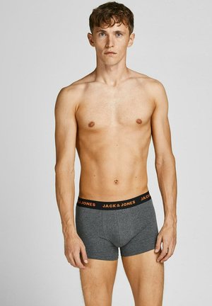 Young man with light skin and short brown hair wearing gray Jack & Jones boxer briefs, standing against a plain light gray background.