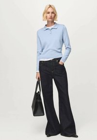 Helles blaues Langarm-Polo-Sweatshirt, kombiniert mit hoch geschnittenen, dunklen Jeans mit weitem Bein und einer schwarzen Handtasche. Sauberes, minimalistisches Design.