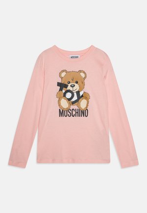 Langermet, lys rosa t-skjorte med et bjørnetrykk som holder et kamera, med "MOSCHINO"-tekst under i svart. Myk bomullsstoff.
