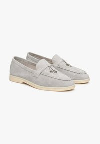 Gray suede loafers with a rounded toe, featuring decorative eyelets and a soft cream-colored rubber sole. Stitching outlines the vamp.