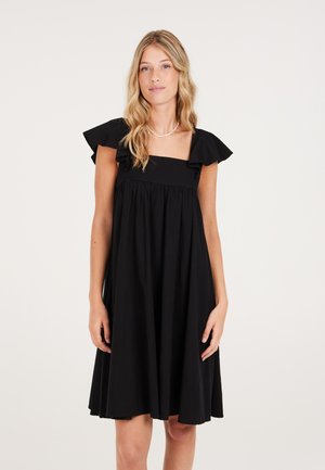 Vestido negro sin mangas con acentos de volantes en los hombros, escote cuadrado y falda fluida. Tejido ligero con una textura suave.