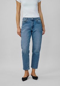Blå denimjeans med rak passform, medelhög midja och femficksdesign. Tyget har en klassisk tvätt med subtila slitageeffekter.