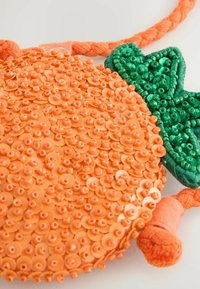 Borsa circolare arancione con paillettes, superficie testurizzata, con accenti di foglie verdi e manico in tessuto intrecciato. Nessun dettaglio aggiuntivo.