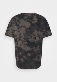 Krátký rukáv tričko v černobílém batikovaném vzoru, vyrobené z měkké bavlny, s volným střihem a zaobleným lemem.