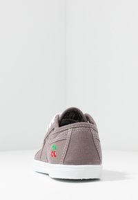 Sneaker in tela grigia con suola bianca, caratterizzata da ciliegie rosse ricamate sul lato e lacci bianchi. La vista posteriore mostra il tessuto testurizzato e le cuciture.