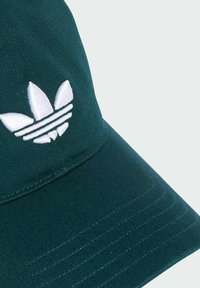 Casquette verte en tissu avec une visière cousue et un logo à trois rayures brodé en blanc sur le devant. Surface texturée.