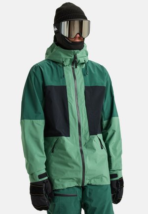 Grüne und schwarze Skijacke mit Kapuze, Reißverschluss vorne, elastischen Bündchen und Mehrpanelen-Design. Hergestellt aus wasserfestem Material.