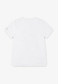 Camiseta blanca de manga corta hecha de algodón. Textura suave, cuello redondo y un detalle de costura simple en el hombro con una pequeña impresión.
