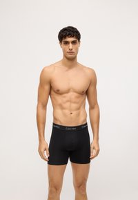 Czarne slipy Calvin Klein o dopasowanym kroju, z elastycznym paskiem w talii i subtelnym logo. Gładki materiał o matowym wykończeniu.