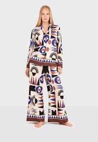 Patterned loungewear set featuring a multi-colored geometric design. The top has a collar; pants are wide-leg with a striped hem.