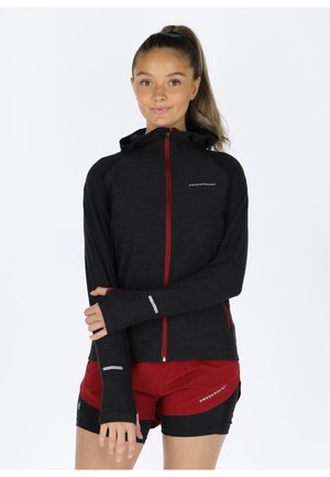 Black zip-up hoodie with red zipper, long sleeves featuring thumbholes, and reflective accents. Paired with red and black athletic shorts.