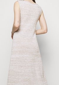 Abito senza maniche in maglia beige con una vestibilità rilassata e una morbida texture, caratterizzato da una silhouette dritta e un motivo sottile su tutta la superficie.