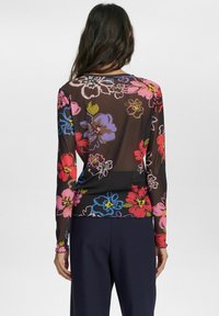 Top trasparente a maniche lunghe con sfondo nero e un vivace motivo floreale in tonalità di rosso, rosa, blu e verde. Tessuto morbido e leggero.