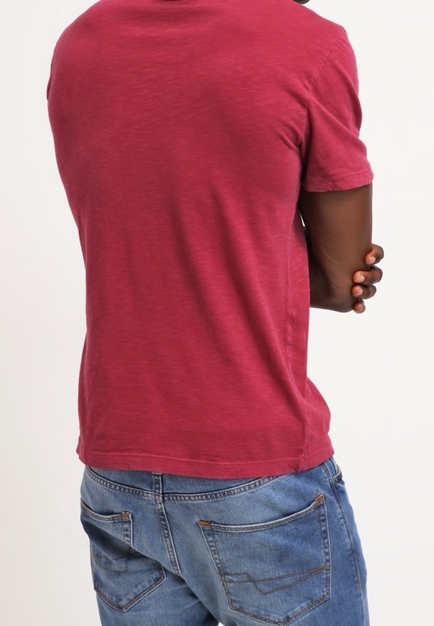 Kurzærmet t-shirt i dyb maroon, lavet af blødt stof med en let tekstur, parret med lyseblå denimjeans med baglommer.