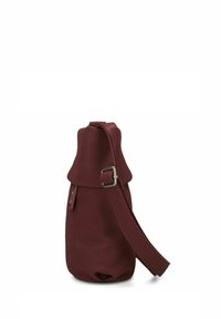 Bolso de cuero marrón con una forma única, que presenta una correa con hebilla, textura suave y parte superior fruncida, diseñado para un aspecto moderno.