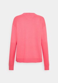Pull rose vif à manches longues et col rond avec poignets et ourlet côtelés, ainsi qu’un petit détail tricoté triangulaire au dos de l’encolure.