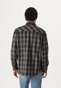 Black and white plaid shirt with long sleeves, button-down collar, and a soft texture. Features contrasting check patterns on fabric.