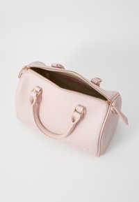 Bolsa de mão em couro texturizado rosa claro, com alças duplas, detalhes em dourado e uma abertura sem fecho que revela um interior bege.