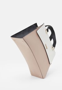 Sac à main structuré avec un extérieur beige et blanc, un intérieur noir, des accents en métal doré, et un design unique en angle.