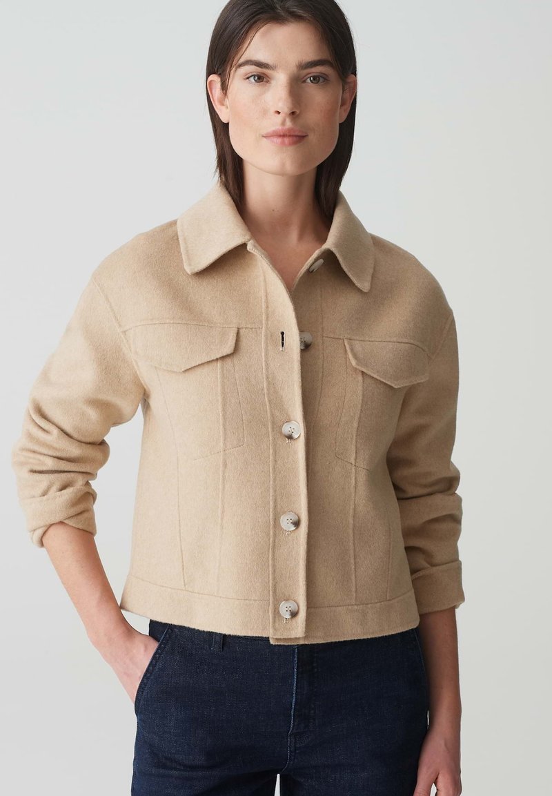 Beige wollen blend jas met een kraag, knoopsluiting en twee borstzakken. Met een cropped ontwerp en opgerolde mouwen.