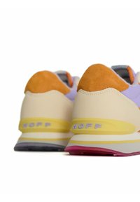 Sneakers met een beige bovenkant, oranje suède accenten, paarse details en een meerkleurige zool met gele en roze secties.