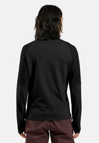 Schwarzes langärmeliges Sportshirt mit glatter Textur, Raglanärmeln und subtilen Musterkontrasten über Schultern und Armen.