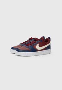 Sneakers Nike com uma mistura de couro borgonha e azul-marinho, com logotipo swoosh branco, detalhes texturizados e sola de borracha branca.