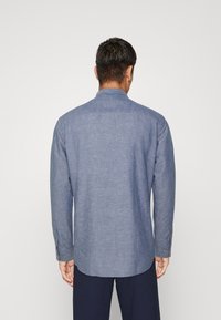 Camicia a maniche lunghe in tessuto azzurro chiaro, con colletto a punta e polsini a due bottoni, orlo dritto e una sottile texture.