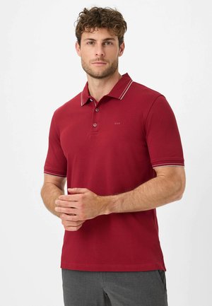 Rotes Poloshirt mit klassischem Kragen, zwei Knöpfen und kontrastierenden Verzierungen am Kragen und an den Ärmeln. Weiches Baumwollmaterial.