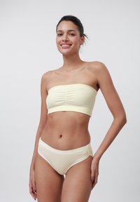 Keltainen ribbitekstiilistä valmistettu bandeau-toppi, joka on yhdistetty samansävyisiin korkeavyötäröisiin alushousuihin. Pehmeä kangas, istuva muotoilu, jossa on kootut yksityiskohdat päällä.