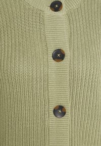 Gebreid vest in lichtgroen met een ribbelstructuur. Voorzien van vier grote zwarte knopen met een schildpadaccent.