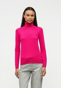 Fuchsia turtleneck sweater, soft texture, slim fit, ribbed cuffs and hem, paired with light gray pants.