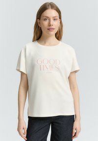 T-shirt blanc à manches courtes avec un col rond et un texte imprimé "GOOD TIMES" en rose clair. Tissu doux avec un léger tombé.