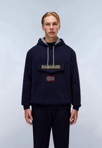 Sudadera con capucha de color azul marino con un forro interior gris, que presenta un parche de logo en la parte frontal y un pequeño detalle de la bandera noruega. Fabricada con tela suave, corte holgado.