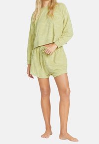 Světle zelená souprava na volný čas obsahující texturovanou zkrácenou mikinu a odpovídající kraťasy s elastickým pasem a volným střihem.