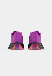 Baskets de sport violettes avec une semelle noire, une tige en mesh et des accents en caoutchouc. Présentent un design texturé et des éléments de rembourrage visibles.