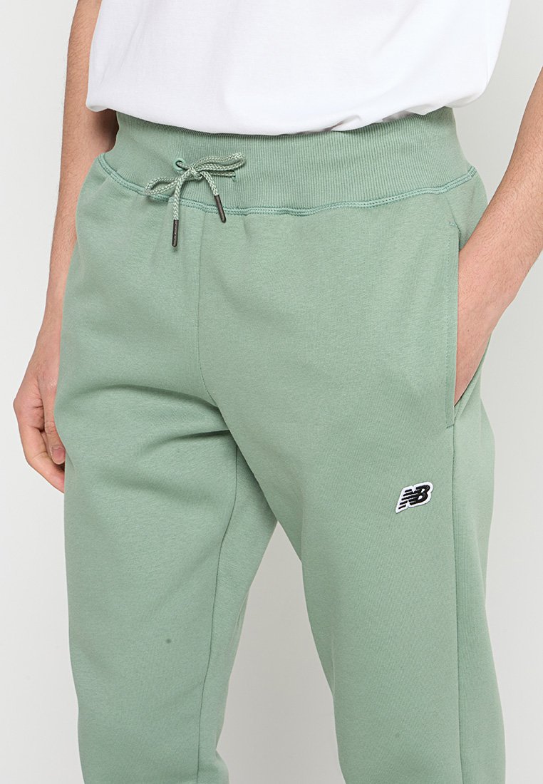 Helle grüne Sweatpants aus weichem Stoff, mit einem Kordelzugbund und Seitentaschen. Beinhaltet ein kleines schwarzes Logo am linken Bein.