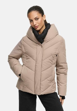 Beige gewatteerde jas met een grote zwarte kraag, zigzagpatroon en knopen aan de voorkant. Voorzien van zijzakken en een gladde textuur.