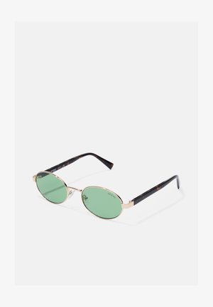 Gafas de sol ovaladas con lentes verdes y marco de metal dorado. Patillas con patrón de carey negro y detalles de la marca.