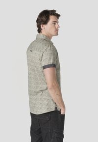 Light gray textured short-sleeve shirt with a collared neckline and dark cuff accents. Features a logo tag on the back.