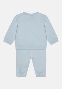 Tuta per bambini in cotone azzurro chiaro, con maniche lunghe, polsini elasticizzati e un design semplice. Nessun motivo o accessorio visibile.