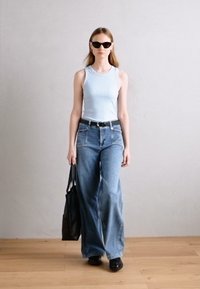 Lys blå ribbet tanktopp, vide blå jeans, svart belte, svart bag, og solbriller. Glatt stoff, avslappet passform, uformelt utseende.