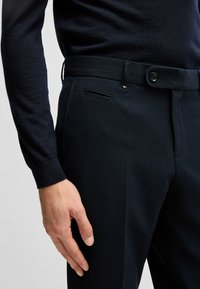 Marinblå texturerade byxor har en standard midja, enkel knappstängning och en sidoficka, med en figurnära passform.